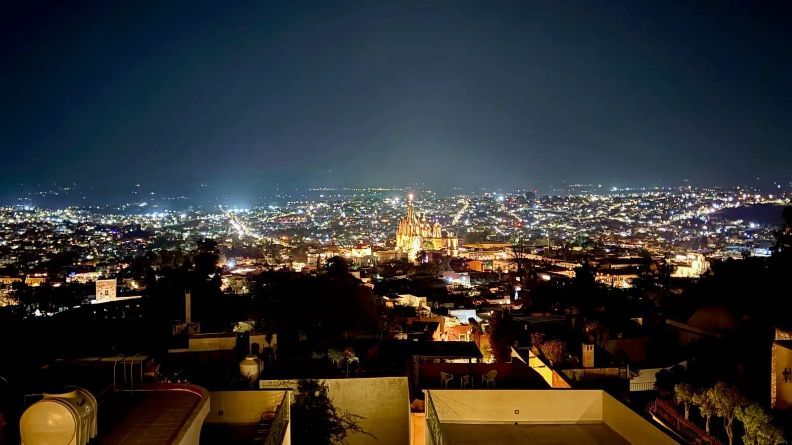 Nighttime view of San Miguel de Allende rooftops with the Parroquia lit up in the distance